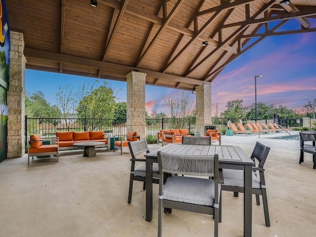 patio terrace at dusk featuring a gazebo, an outdoor living space, and a fenced in pool