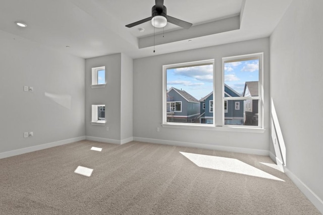 spare room featuring ceiling fan, carpet flooring, a raised ceiling, and baseboards