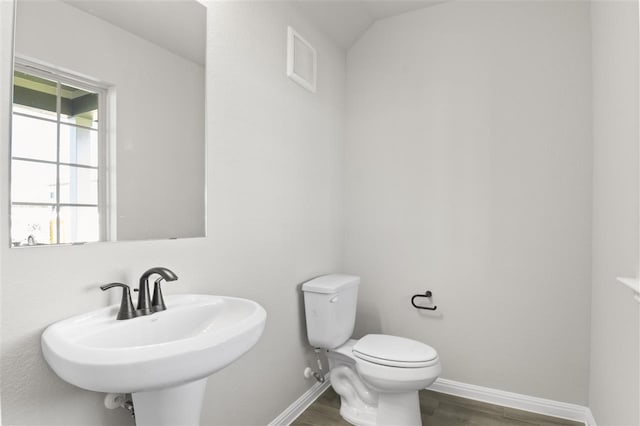 bathroom with toilet, wood-type flooring, vaulted ceiling, and sink