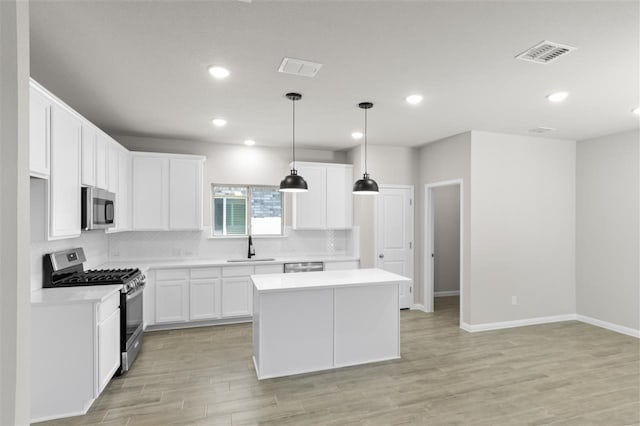 kitchen featuring pendant lighting, white cabinetry, appliances with stainless steel finishes, and a center island