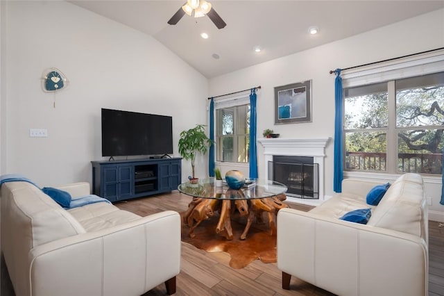 living room featuring ceiling fan, light wood-type flooring, and lofted ceiling