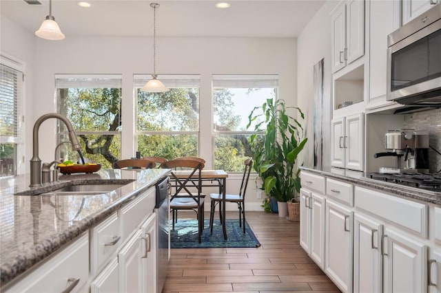 kitchen with white cabinets, appliances with stainless steel finishes, sink, and pendant lighting