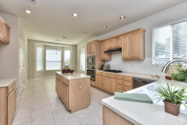 kitchen with decorative backsplash, appliances with stainless steel finishes, light brown cabinetry, pendant lighting, and a kitchen island