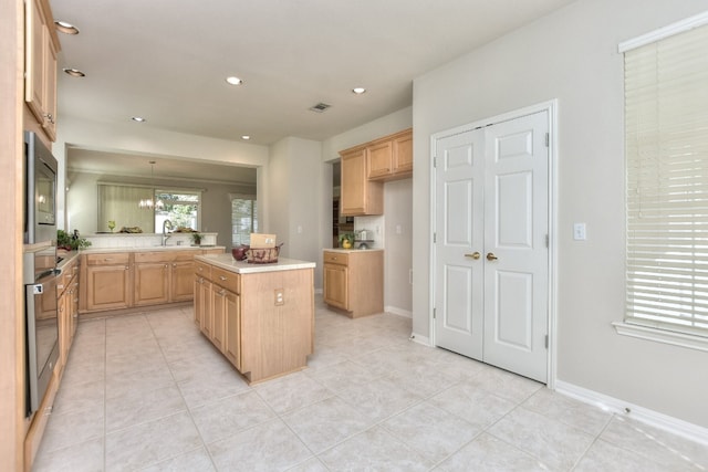 kitchen featuring light brown cabinets, a center island, an inviting chandelier, hanging light fixtures, and appliances with stainless steel finishes