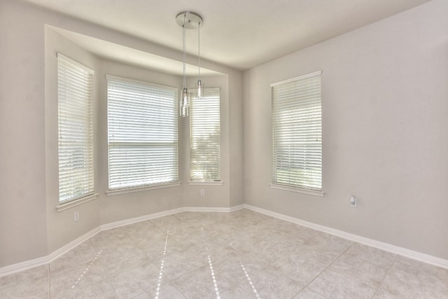 spare room featuring a chandelier and a healthy amount of sunlight