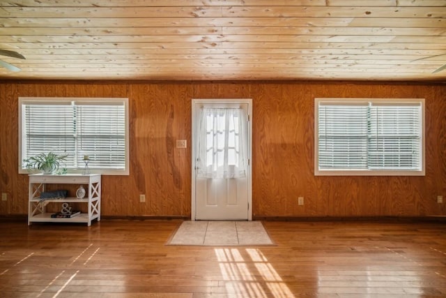 entryway with plenty of natural light, wood ceiling, and wood walls