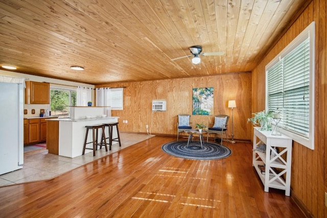 192 Carmen Hill Ln, Bastrop, TX 78602 - living area featuring wooden ceiling, wood walls, light wood-type flooring, a ceiling fan, and an AC wall unit