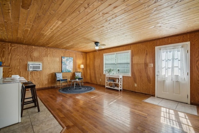 sitting room with a healthy amount of sunlight, a wall mounted air conditioner, wood ceiling, and wooden walls