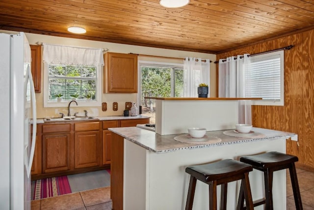 192 Carmen Hill Ln, Bastrop, TX 78602 - kitchen featuring freestanding refrigerator, wooden ceiling, light tile patterned flooring, a kitchen bar, and light countertops