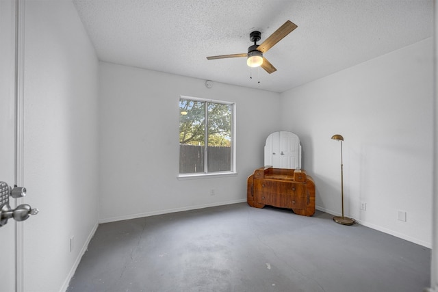 empty room with ceiling fan, concrete floors, and a textured ceiling