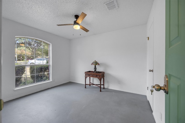 unfurnished room with ceiling fan, concrete flooring, and a textured ceiling