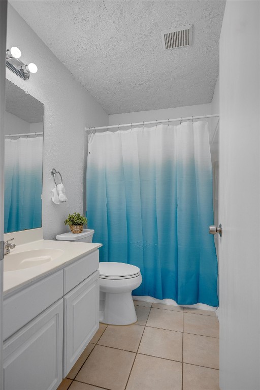 bathroom with vanity, tile patterned flooring, a shower with shower curtain, toilet, and a textured ceiling