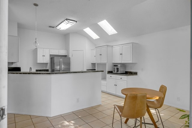 kitchen with white cabinets, decorative light fixtures, kitchen peninsula, and stainless steel refrigerator