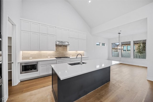 kitchen with pendant lighting, white cabinets, sink, built in microwave, and gas cooktop