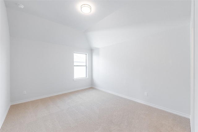 empty room with light colored carpet and vaulted ceiling