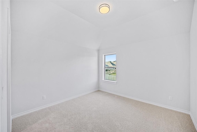 spare room featuring vaulted ceiling and light colored carpet