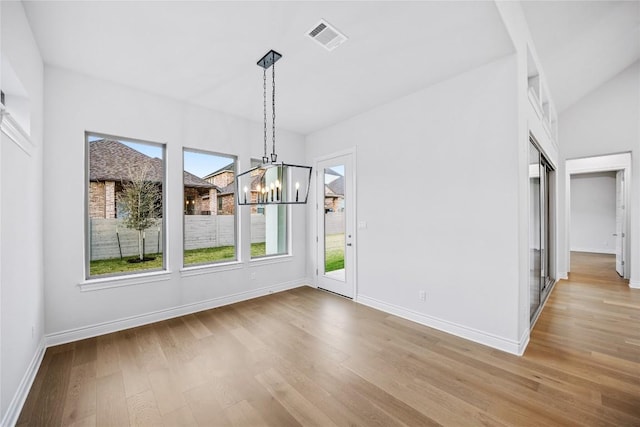 unfurnished dining area with a notable chandelier and light hardwood / wood-style floors