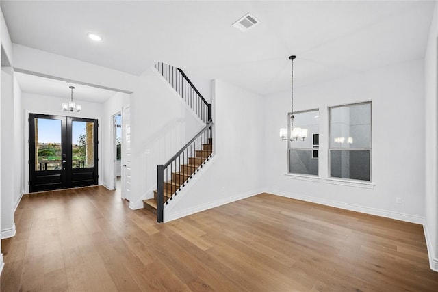 entrance foyer with an inviting chandelier, hardwood / wood-style floors, and french doors