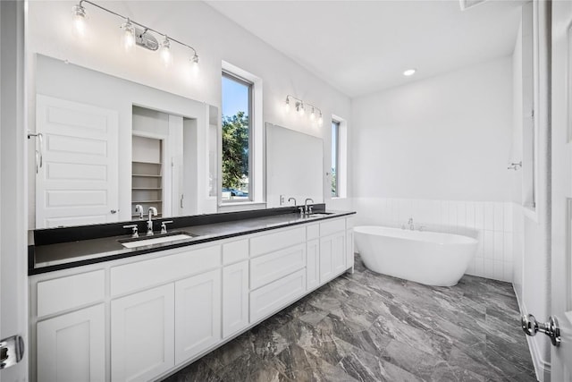 bathroom with tile walls, vanity, and a bathtub