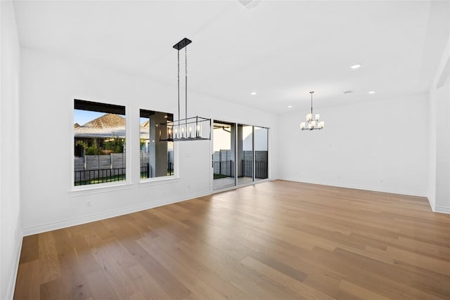 unfurnished living room with light wood-type flooring and a notable chandelier