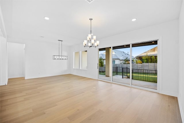 unfurnished room with light hardwood / wood-style floors and an inviting chandelier