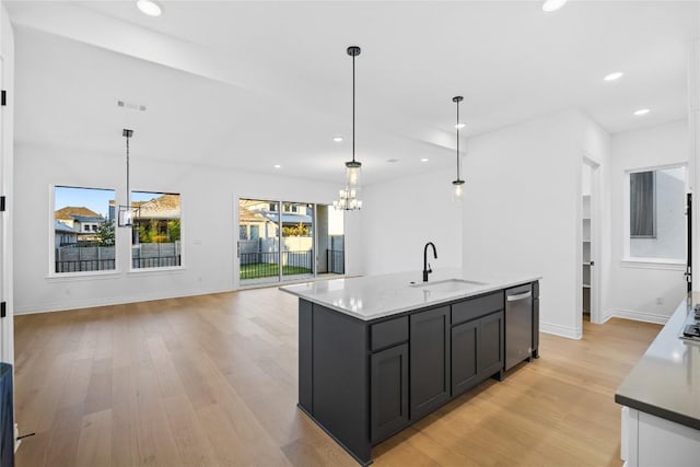 kitchen with a kitchen island with sink, sink, pendant lighting, and light hardwood / wood-style flooring