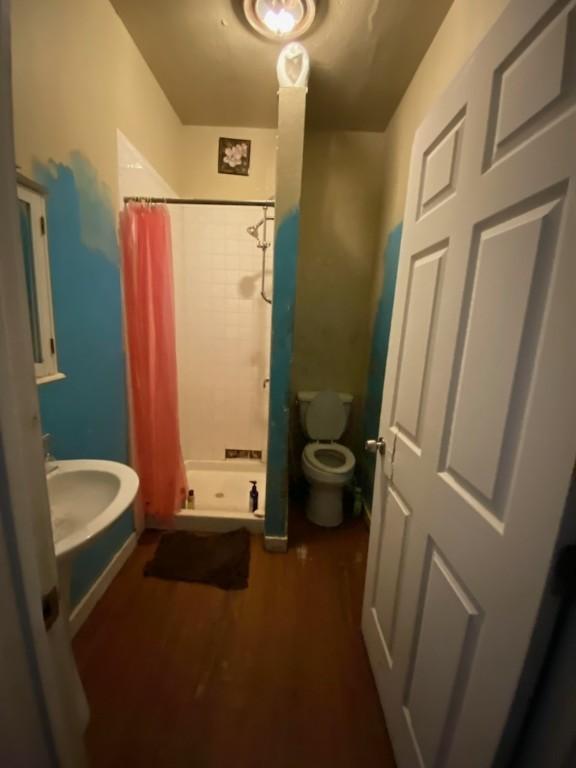 bathroom featuring hardwood / wood-style floors, toilet, and walk in shower