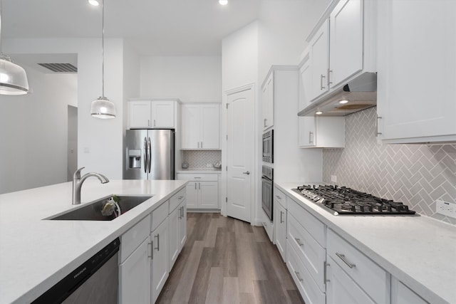 kitchen with stainless steel appliances, sink, hardwood / wood-style flooring, white cabinets, and hanging light fixtures