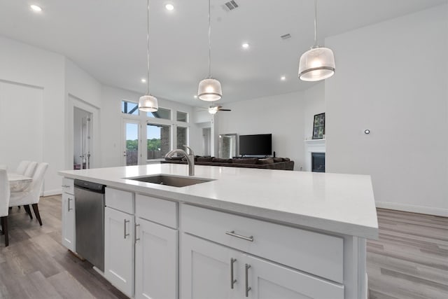 kitchen featuring dishwasher, white cabinets, sink, hanging light fixtures, and light hardwood / wood-style floors