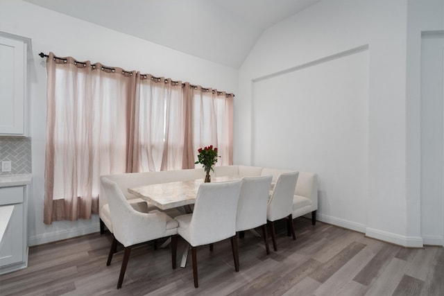 dining room featuring light wood-type flooring and vaulted ceiling