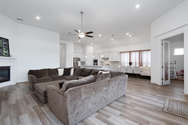 living room with ceiling fan, a healthy amount of sunlight, and light wood-type flooring