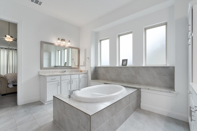 bathroom featuring tile patterned flooring, ceiling fan, a relaxing tiled tub, and vanity