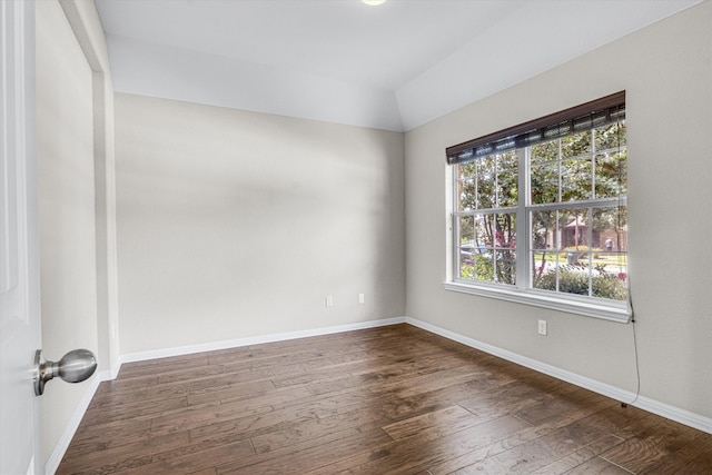 unfurnished room with a wealth of natural light, dark wood-type flooring, and vaulted ceiling