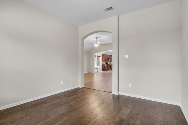 unfurnished room featuring dark hardwood / wood-style flooring, vaulted ceiling, and ceiling fan