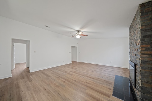 unfurnished living room with ceiling fan, light hardwood / wood-style flooring, and a brick fireplace