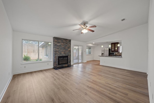 unfurnished living room featuring ceiling fan, light hardwood / wood-style floors, lofted ceiling, and a fireplace