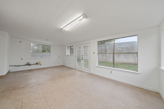 empty room featuring a healthy amount of sunlight, light tile patterned floors, and a textured ceiling