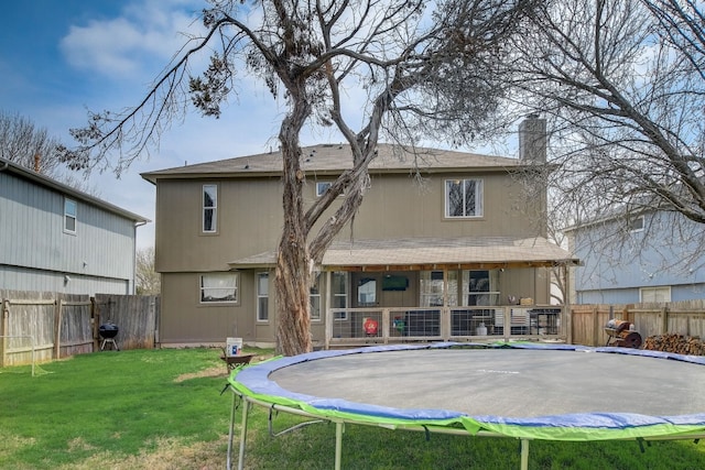 back of property featuring a trampoline and a lawn