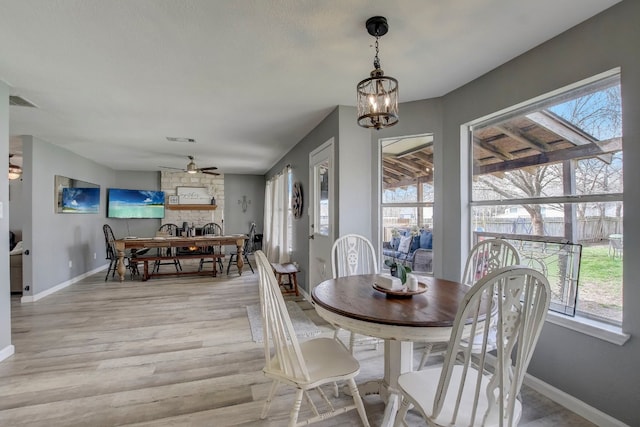 dining space with ceiling fan with notable chandelier, a healthy amount of sunlight, and light wood-type flooring