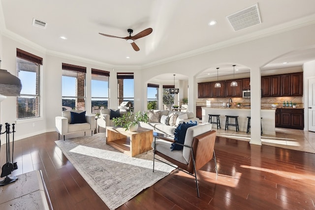 living room with ceiling fan, dark hardwood / wood-style flooring, ornamental molding, and a wealth of natural light