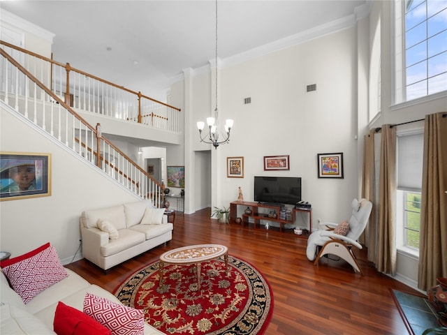 living room featuring a towering ceiling, dark hardwood / wood-style floors, ornamental molding, and a notable chandelier