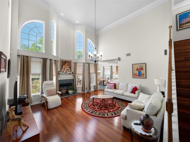 living room featuring hardwood / wood-style floors, a tile fireplace, a towering ceiling, and a wealth of natural light