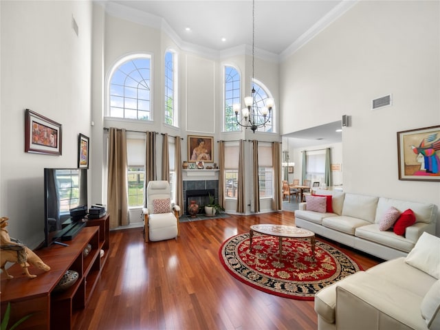 living room with a towering ceiling, hardwood / wood-style flooring, plenty of natural light, and a tiled fireplace