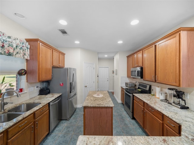 kitchen featuring light stone countertops, sink, a center island, tile patterned floors, and appliances with stainless steel finishes