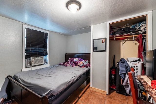 tiled bedroom with cooling unit, a textured ceiling, and a closet