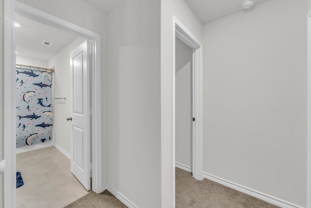 hallway featuring light colored carpet