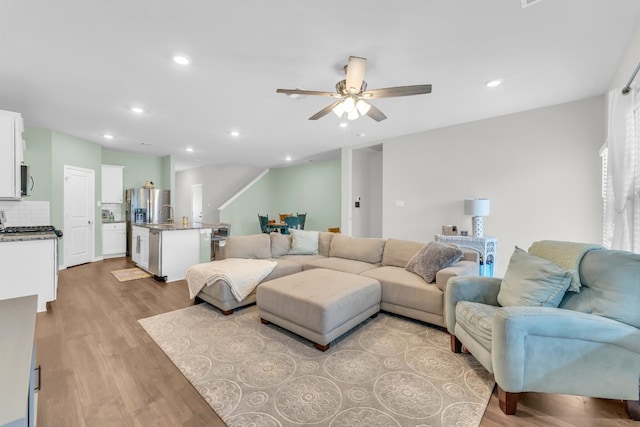 living room featuring ceiling fan and light hardwood / wood-style floors