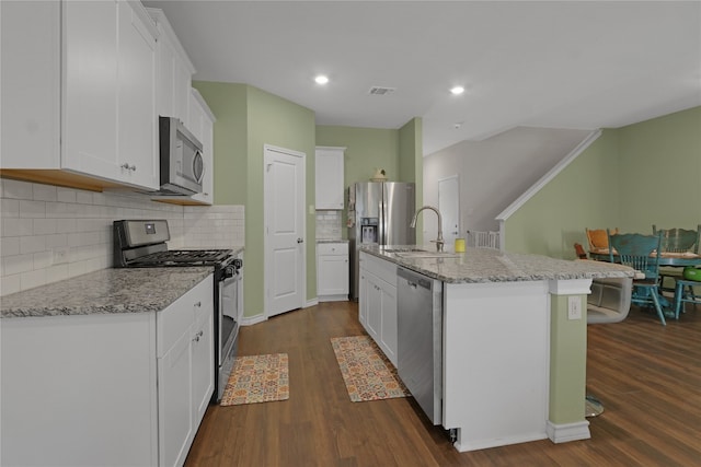 kitchen with white cabinetry, an island with sink, appliances with stainless steel finishes, and dark wood-type flooring