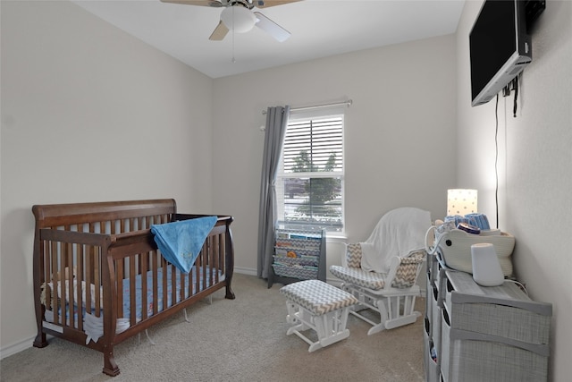 carpeted bedroom with ceiling fan and a crib