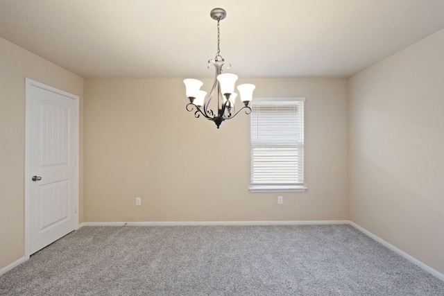 spare room featuring carpet and a notable chandelier